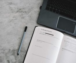 Laptop computer next to daily planner to help student